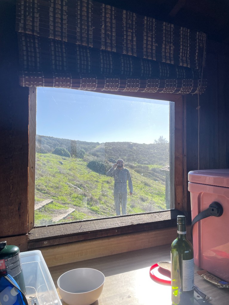 Taylor reflected in a cabin window over rolling hills