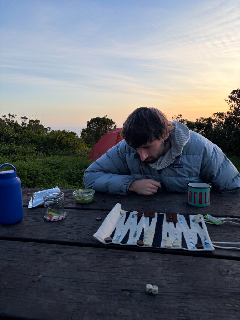 Taylor playing backgammon at sunset on a camping trip